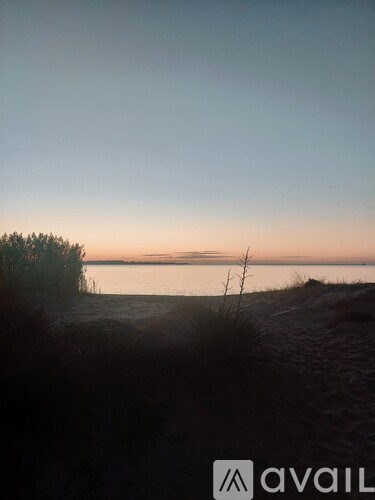 A beach scene with a sunset and a logo in the bottom right corner.