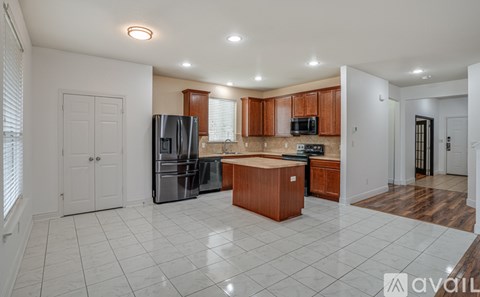 A kitchen with white tiled floors and wooden cabinets.