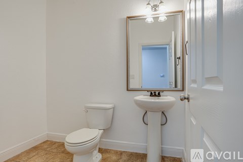 A bathroom with a toilet, sink and mirror.