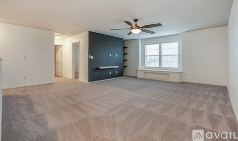 A room with a ceiling fan and carpeted floor.
