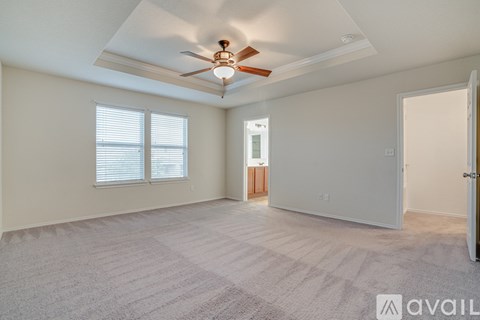 A spacious room with a ceiling fan and carpeted floor.