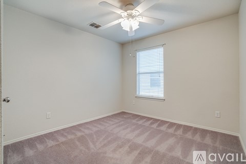 A room with a ceiling fan and a window with blinds.
