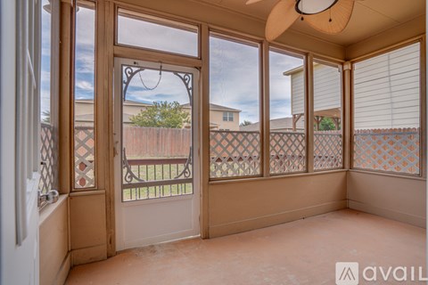 A sunroom with a view of a fence and houses.