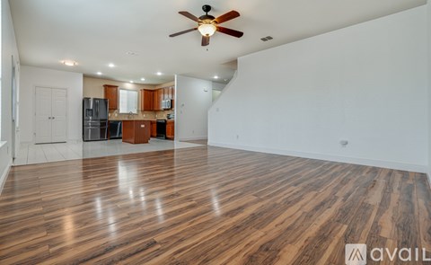 A spacious room with wooden flooring and a ceiling fan.