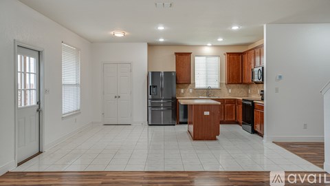 A kitchen with white walls and wooden cabinets is available for rent.