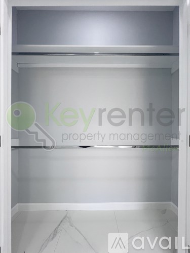 A white empty closet with a logo of Keyrenter Property Management.