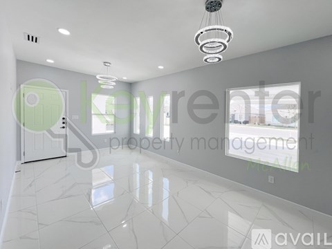 A spacious, well-lit room with a marble floor and a green door.