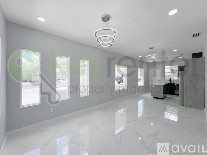 A spacious, well-lit room with a marble floor and a modern chandelier.