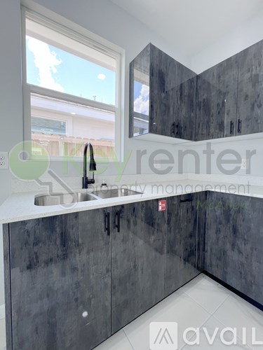 A kitchen with dark grey cabinets and a white countertop.