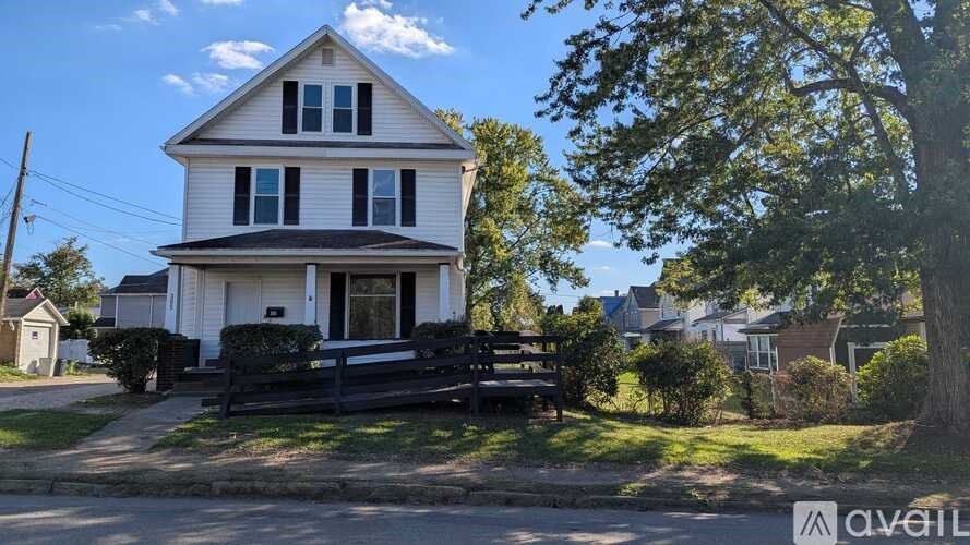 A white house with a black fence and a tree in front.