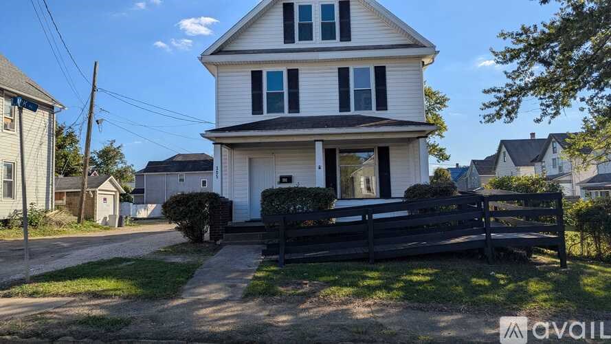 A two-story house with a porch and a black fence.