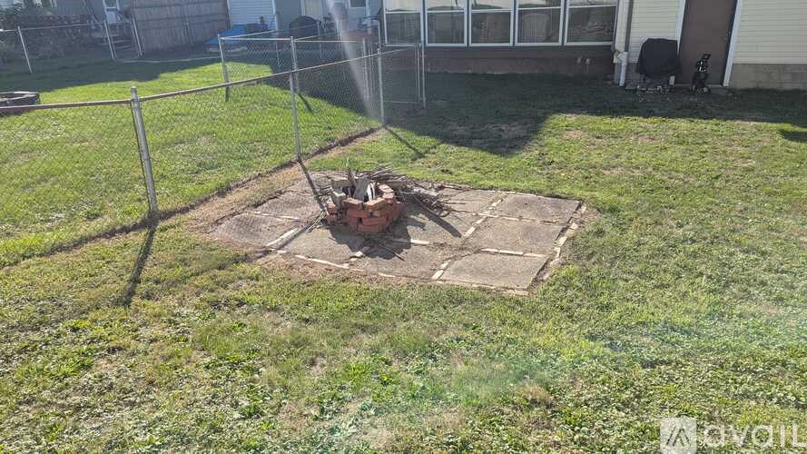 A backyard with a fence and a fire pit.