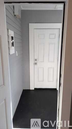 A white door is in a hallway with a black floor.