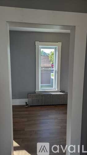 A room with a window and a radiator on the floor.