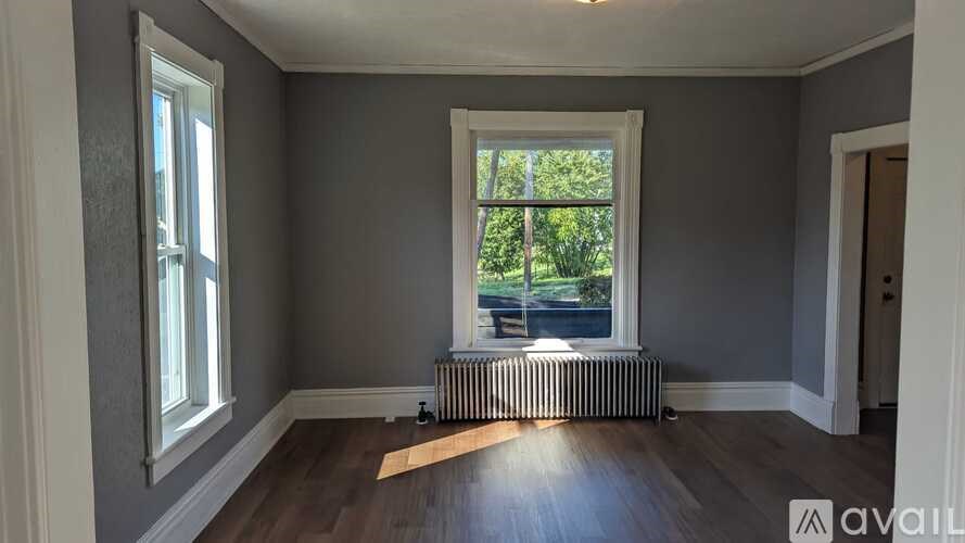 A room with grey walls and a window with a view of trees and a fence.