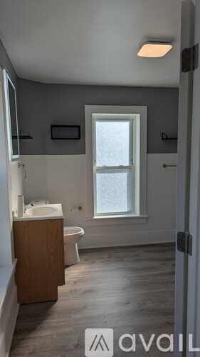 A bathroom with a toilet, sink, and window.