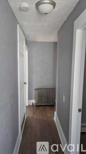 A long hallway with a white ceiling and a radiator on the floor.