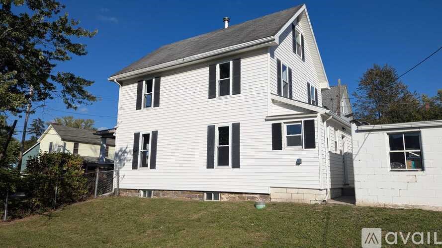 A two-story white house with a grey roof is for sale.