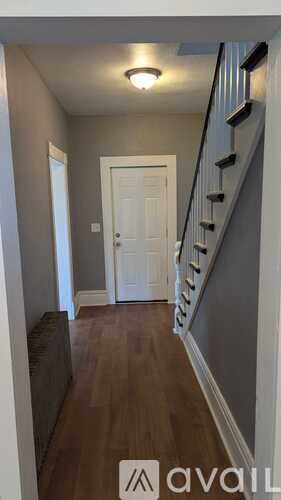 A hallway with a staircase and a white door.