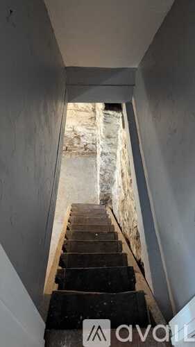A staircase with a metal railing leading to a stone wall.