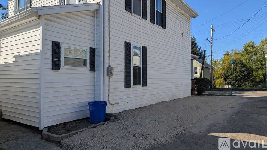 A white house with a blue bucket in front of it.