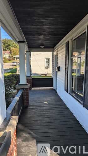 A porch with a black ceiling and a brick column.