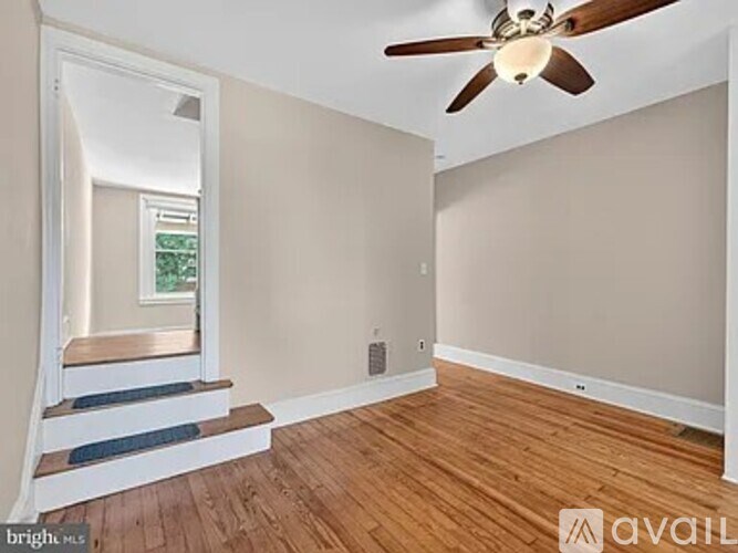 A room with a ceiling fan and wooden flooring.