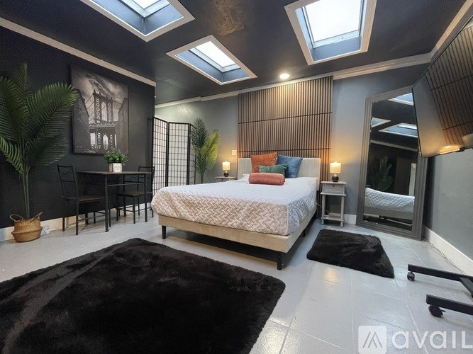 A bedroom with a bed, a chair, and a table with a vase on it.