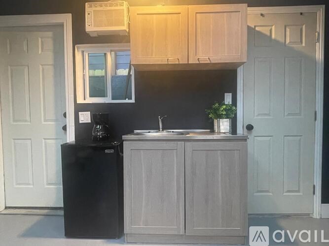 A kitchen with a black fridge and wooden cabinets.