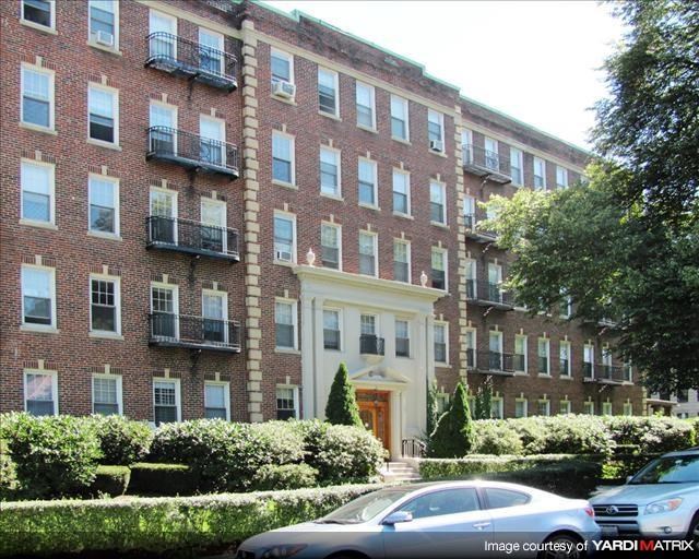 a large brick apartment building with cars parked in front