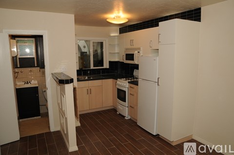 A kitchen with white appliances and brown tile flooring.