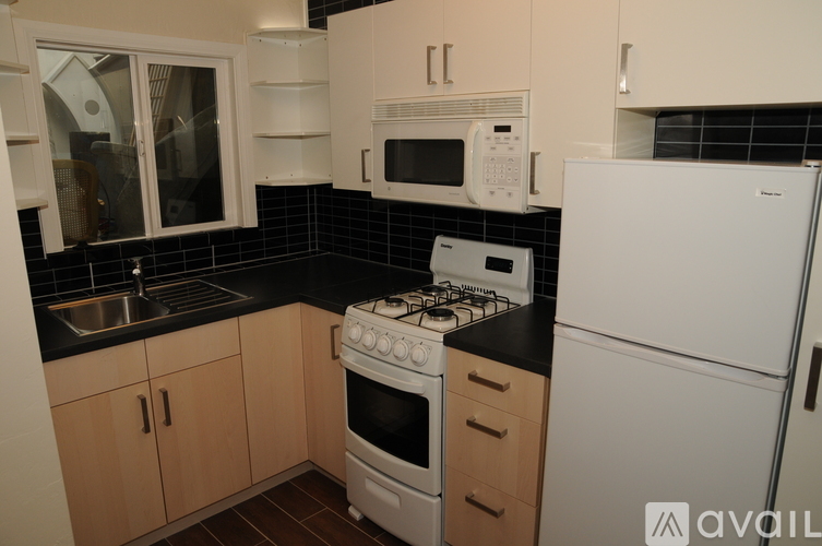 A kitchen with a white fridge, black countertops, and wooden cabinets.