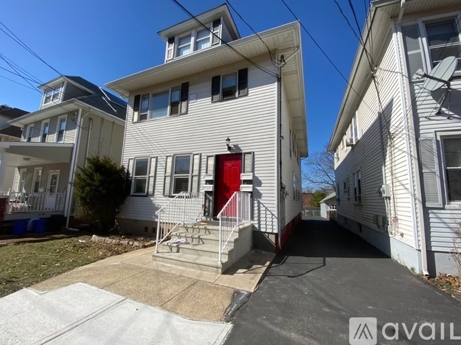 A white house with a red door is for sale.