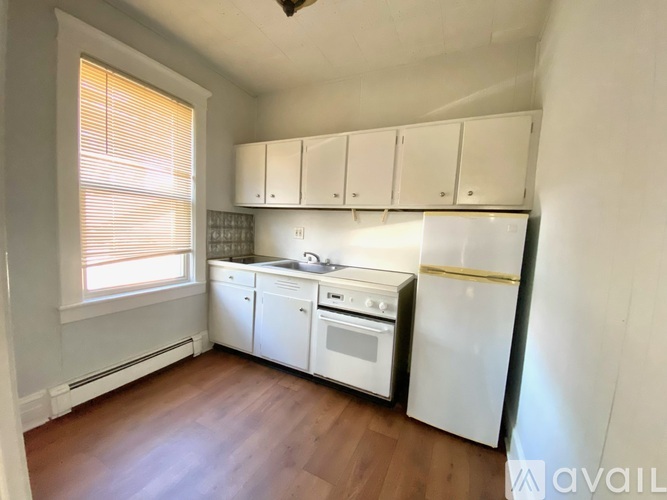 A kitchen with white appliances and wooden floors.