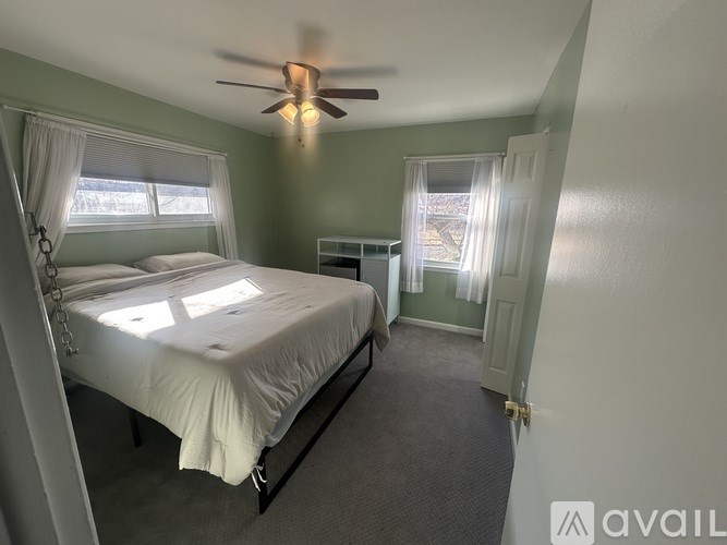 A bedroom with a bed, a ceiling fan, and a window.