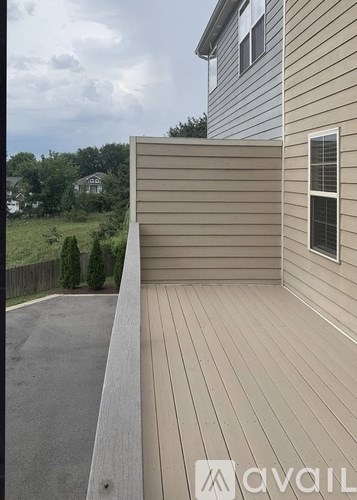 A wooden deck with a window and a wall on the side of a house.