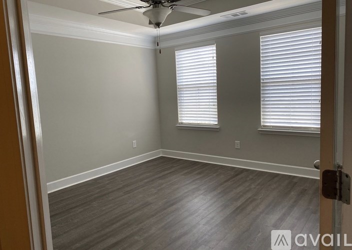 A room with a ceiling fan and two windows with blinds.