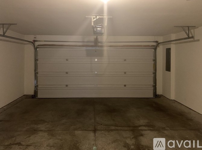 A large garage with a white door and a concrete floor.