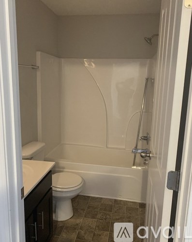 A white toilet sits in a small bathroom with a walk-in shower.