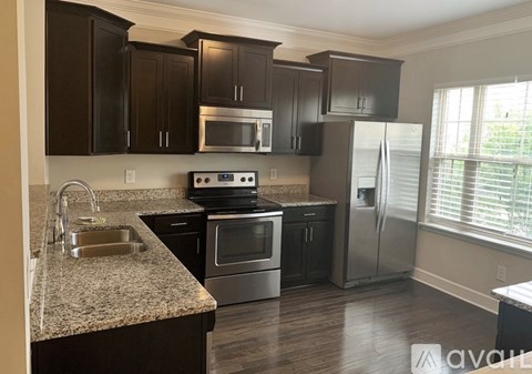 A kitchen with dark brown cabinets and stainless steel appliances.