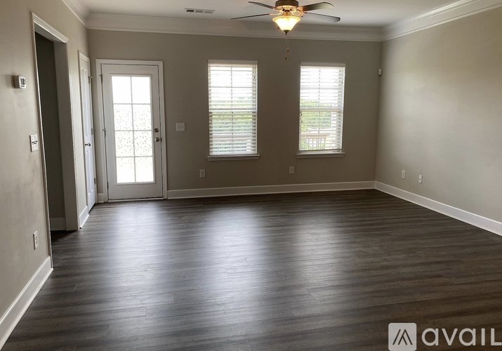 A room with a ceiling fan and three windows.