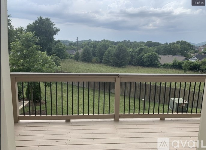 A balcony with a wooden floor and a metal railing overlooking a green landscape.