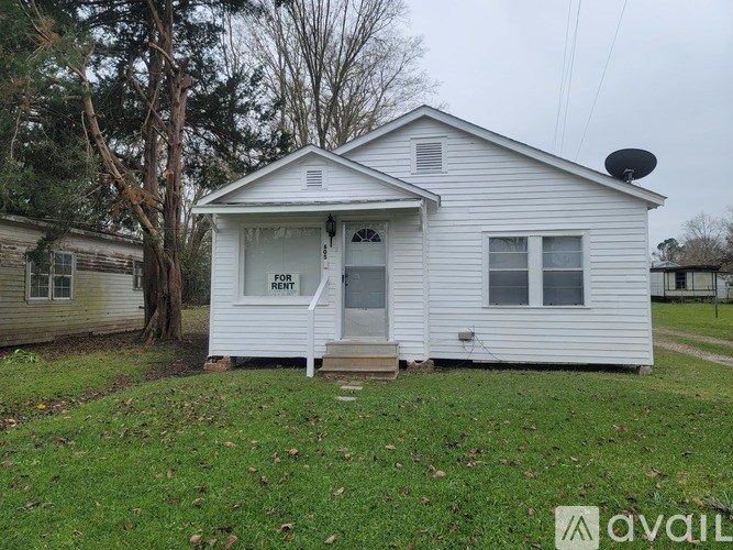 A small white house with a porch and a satellite dish on the roof.