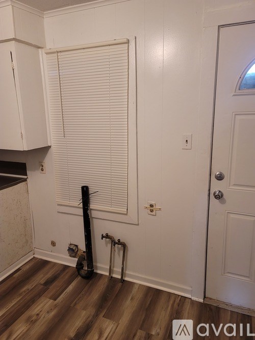 A room with a white door and a guitar leaning against it.