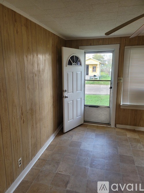 A room with wooden walls and a white door leading to a patio.