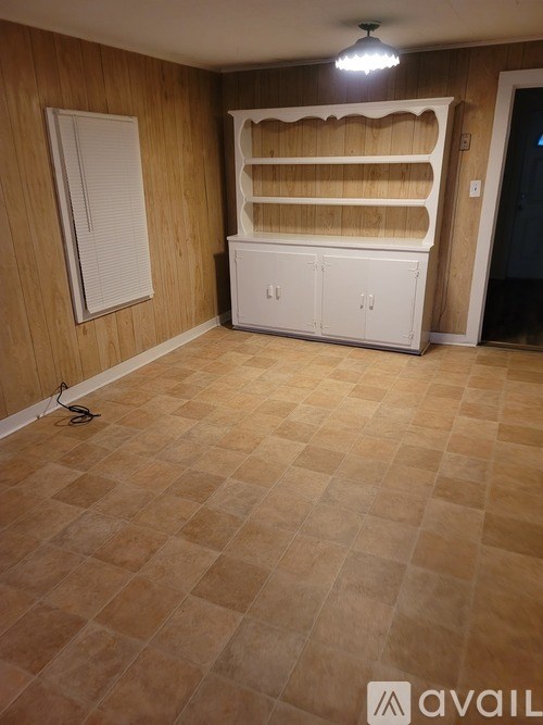 A room with a wooden wall and a white cabinet.