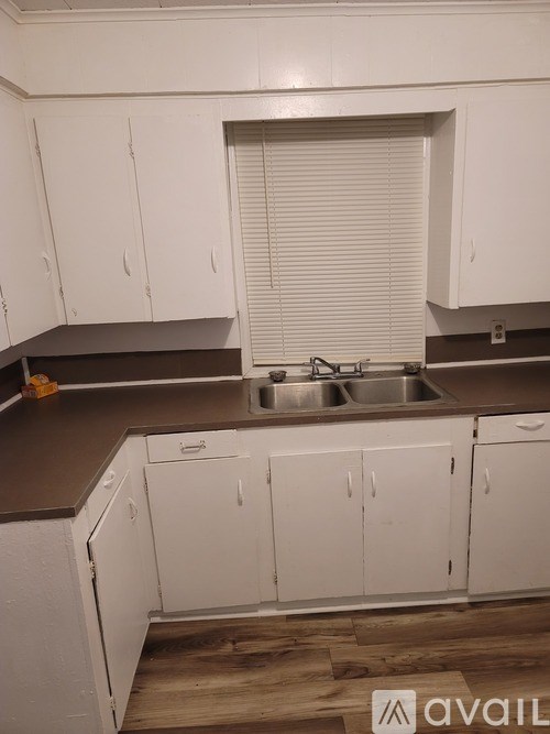 A kitchen with white cabinets and a brown countertop.