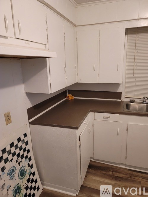 A kitchen with white cabinets and a checkered tile backsplash.