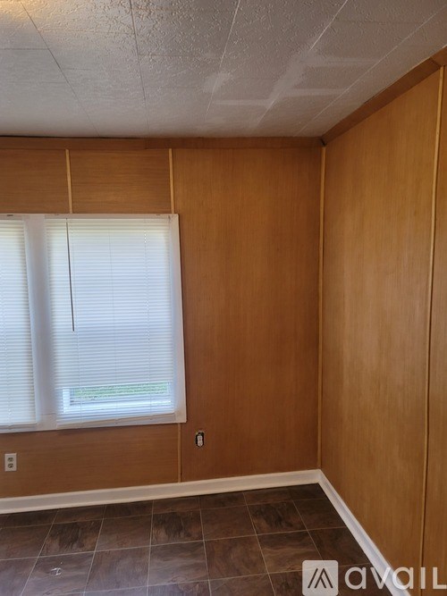 A room with wooden walls and a window with blinds.