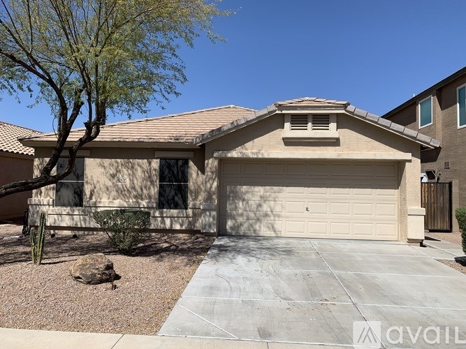 A house with a garage and a tree in front.